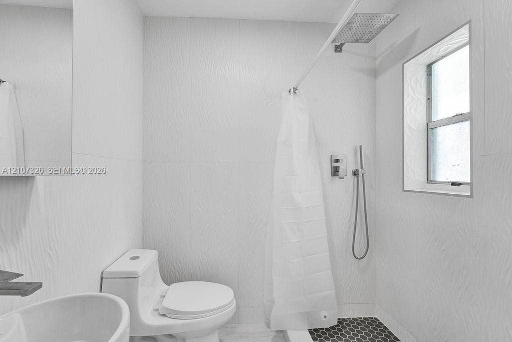 1801 NE 154th Street, #0, North Miami Beach, North Miami Beach, FL 33162 Bathroom featuring textured wall tile, rain-style shower head with handheld attachment, hexagonal floor tile, and a one-piece toilet