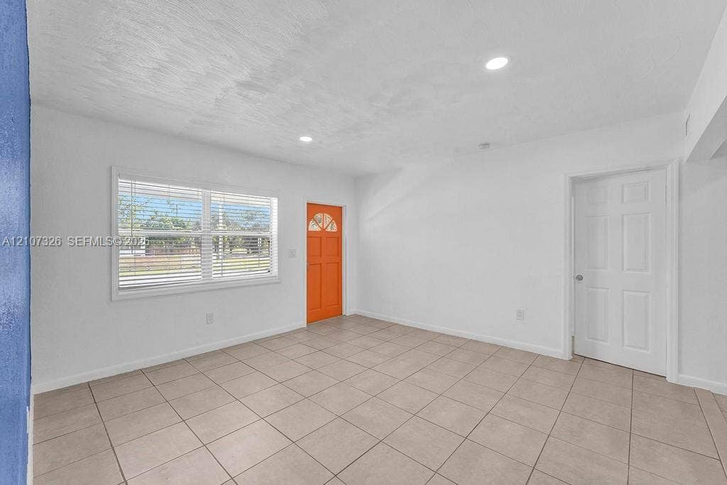 1801 NE 154th Street, #0, North Miami Beach, North Miami Beach, FL 33162 Interior space featuring neutral tile flooring, recessed lighting, a multi-pane entry door, and a horizontal window with adjustable blinds