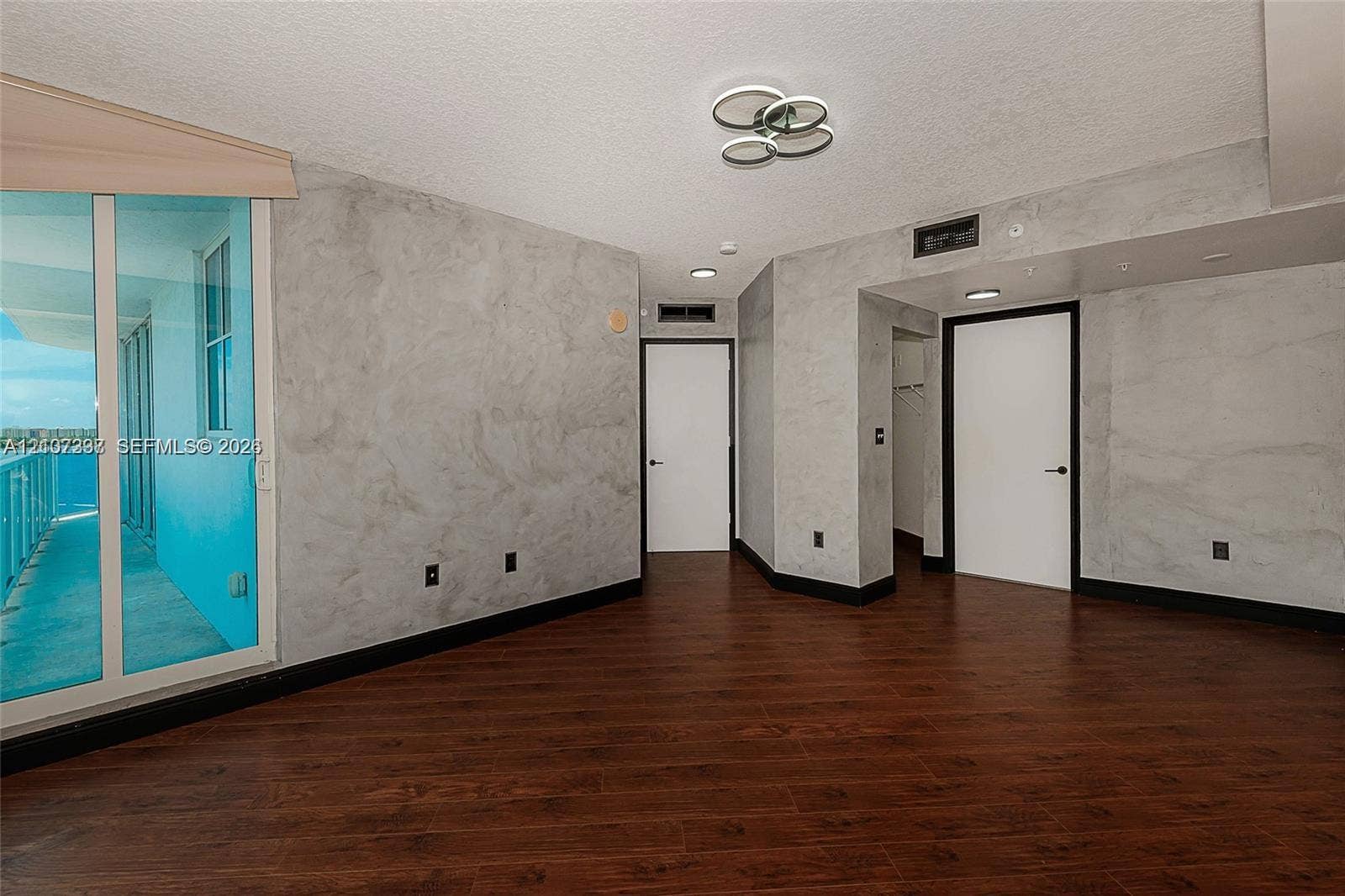 1881 79th St Causeway, #1007, North Bay Village, FL 33141 Interior space featuring wood-finish flooring, decorative wall treatment, multi-light flush mount fixture, and sliding glass door access to an exterior balcony