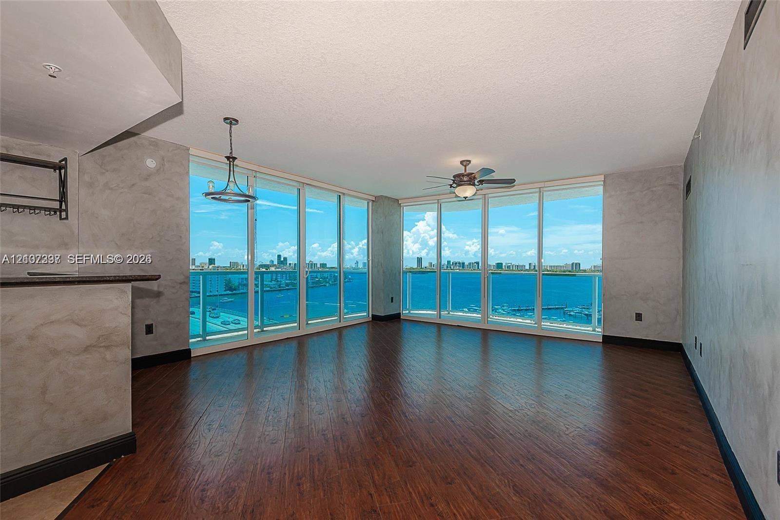 1881 79th St Causeway, #1007, North Bay Village, FL 33141 Living area featuring floor-to-ceiling glass windows, wood-finish flooring, textured wall finishes, and a contemporary pendant light fixture