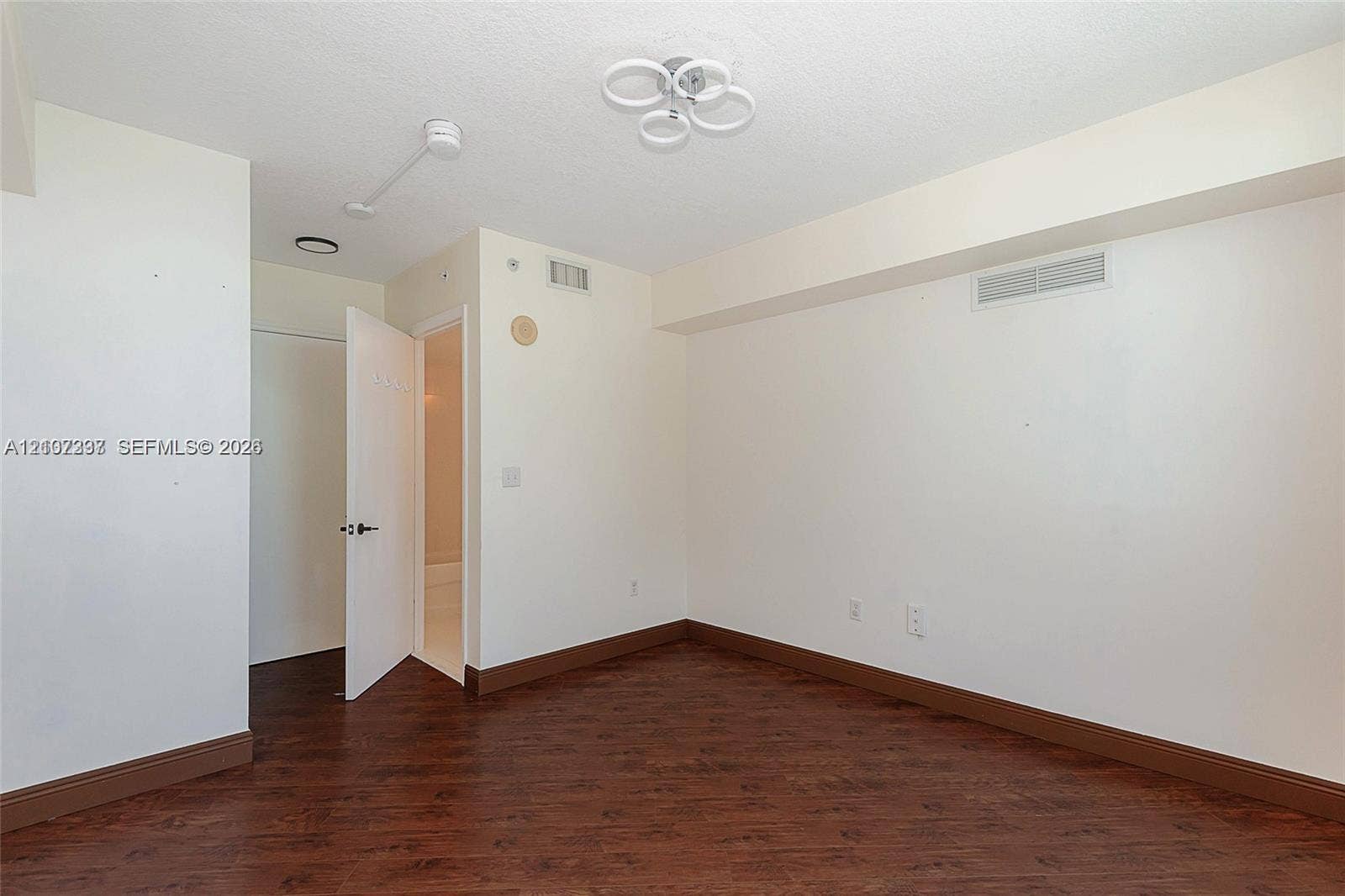 1881 79th St Causeway, #1007, North Bay Village, FL 33141 Interior space featuring wood-finish flooring, a contemporary multi-ring flush mount light fixture, and an open doorway