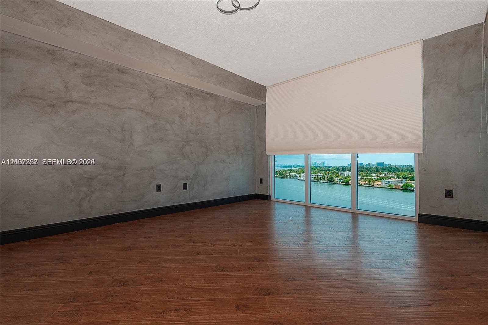 1881 79th St Causeway, #1007, North Bay Village, FL 33141 Room featuring textured gray accent walls, wood-finish flooring, and floor-to-ceiling windows with water scenery