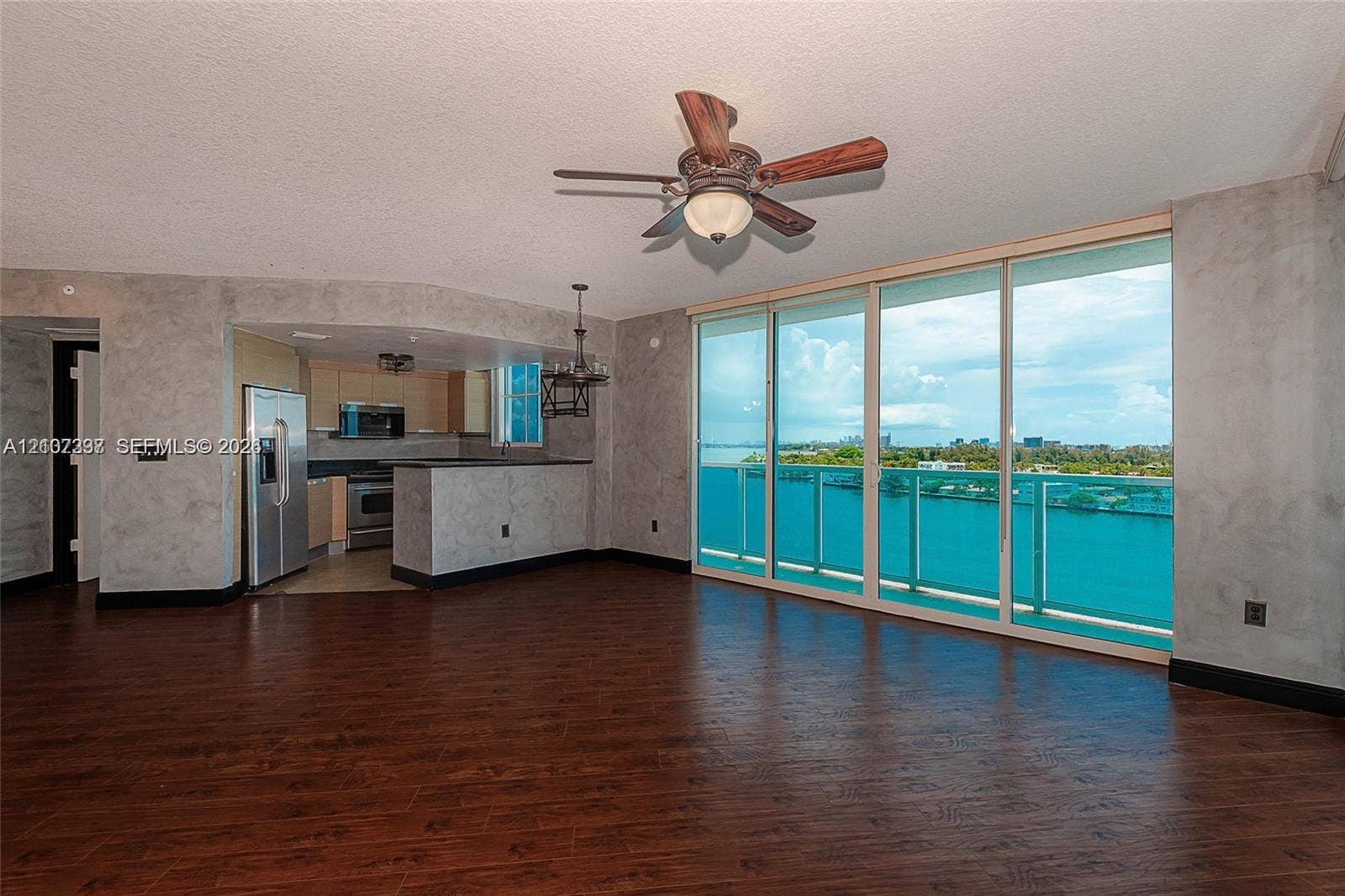 1881 79th St Causeway, #1007, North Bay Village, FL 33141 Wood-finish flooring, floor-to-ceiling glass wall, ceiling fan, and peninsula kitchen counter