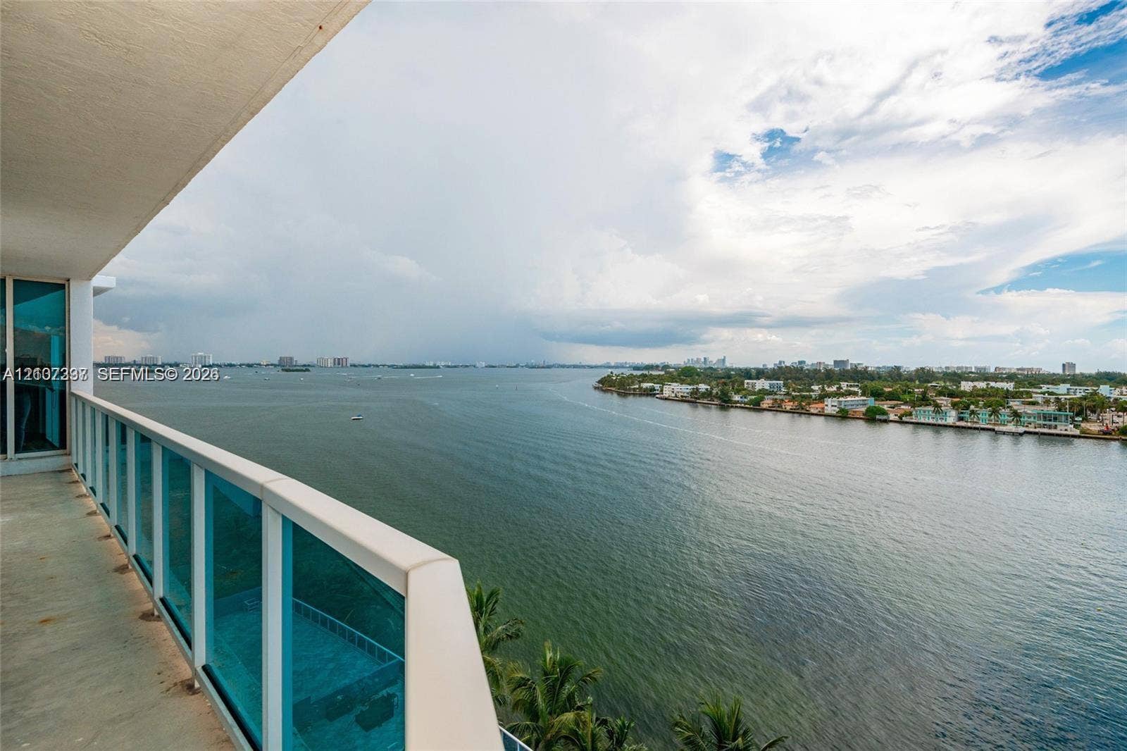 1881 79th St Causeway, #1007, North Bay Village, FL 33141 Covered balcony featuring concrete flooring and a glass-paneled railing with a metal frame, overlooking the water