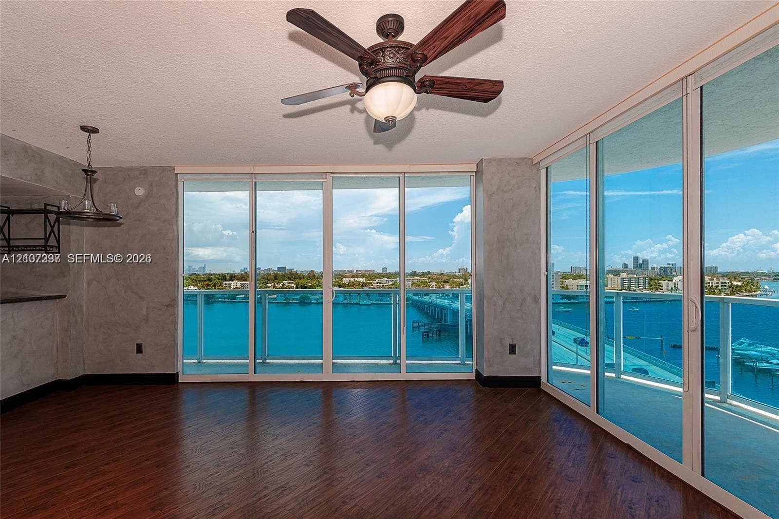 1881 79th St Causeway, #1007, North Bay Village, FL 33141 Floor-to-ceiling sliding glass walls, wood-finish flooring, ceiling fan with integrated light fixture, and textured gray wall finishes
