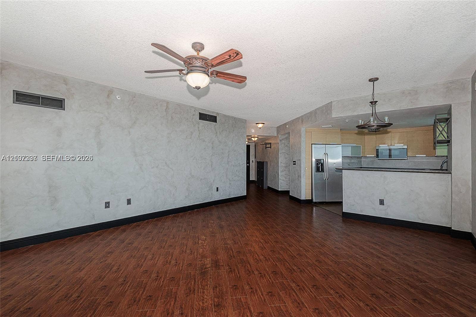 1881 79th St Causeway, #1007, North Bay Village, FL 33141 Living space featuring wood-finish flooring, custom textured wall finishes, a ceiling fan with integrated lighting, and a kitchen equipped with stainless steel appliances and a breakfast bar