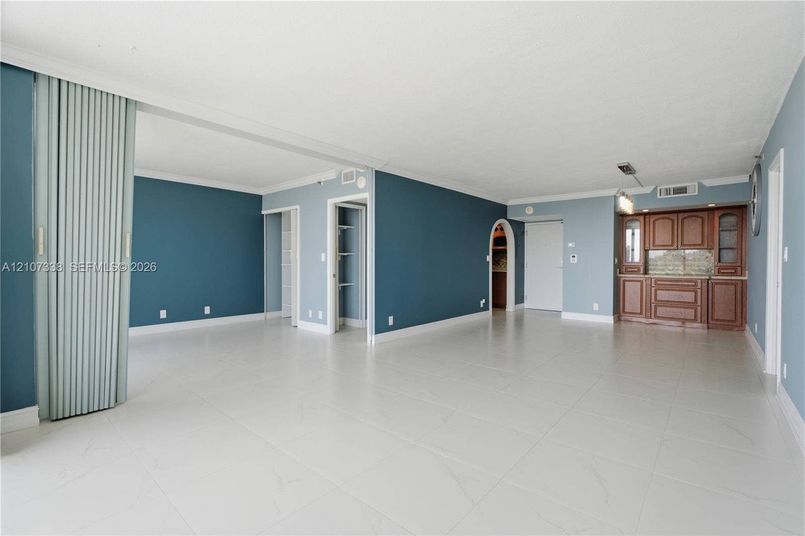 20355 NE 34th Court, #1824, Aventura, FL 33180 Open-concept living space featuring large-format tile flooring, built-in wooden cabinetry, an arched doorway, and a vertical sliding room partition