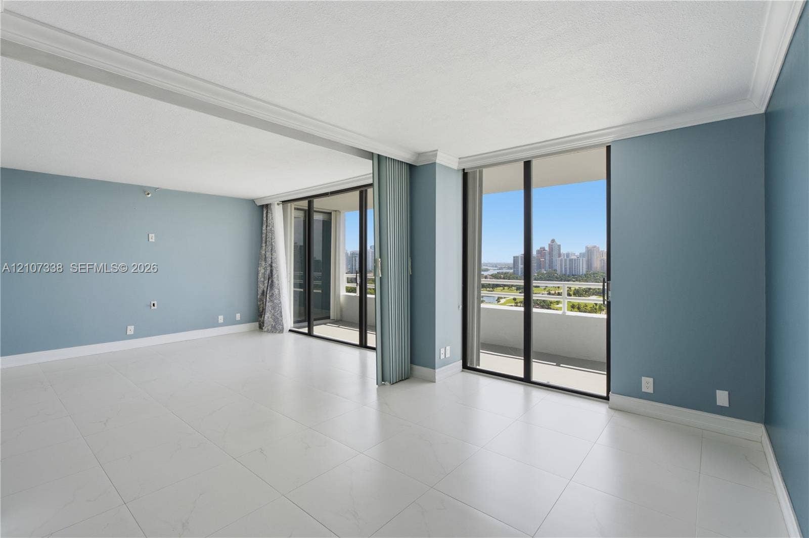 20355 NE 34th Court, #1824, Aventura, FL 33180 Large-format tile flooring, crown molding, and floor-to-ceiling sliding glass doors opening to a balcony with cityscape scenery