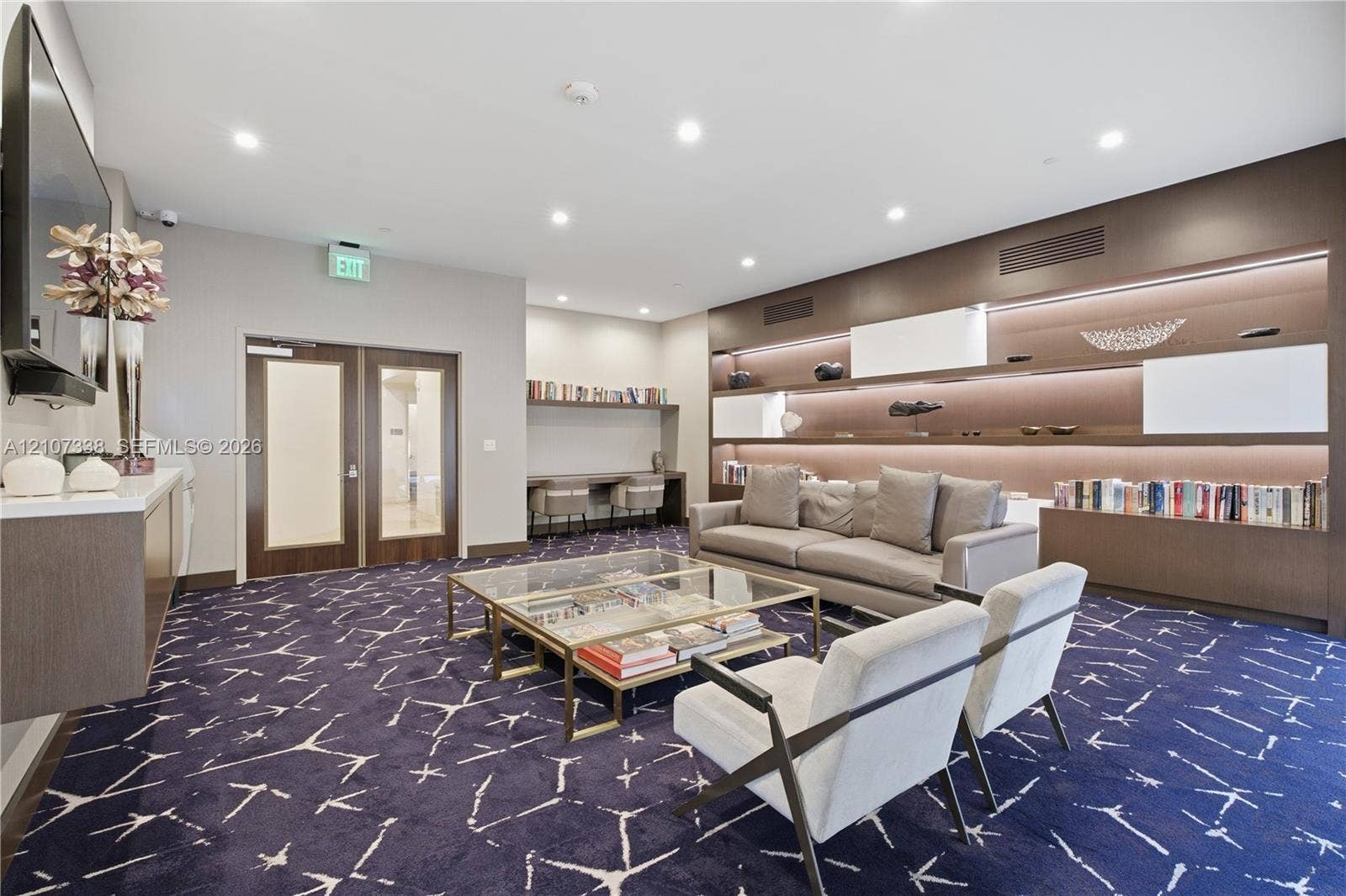 20355 NE 34th Court, #1824, Aventura, FL 33180 Large-format patterned carpeting, expansive wall-to-wall built-in shelving with integrated LED illumination, and a dedicated wood-finish desk workstation