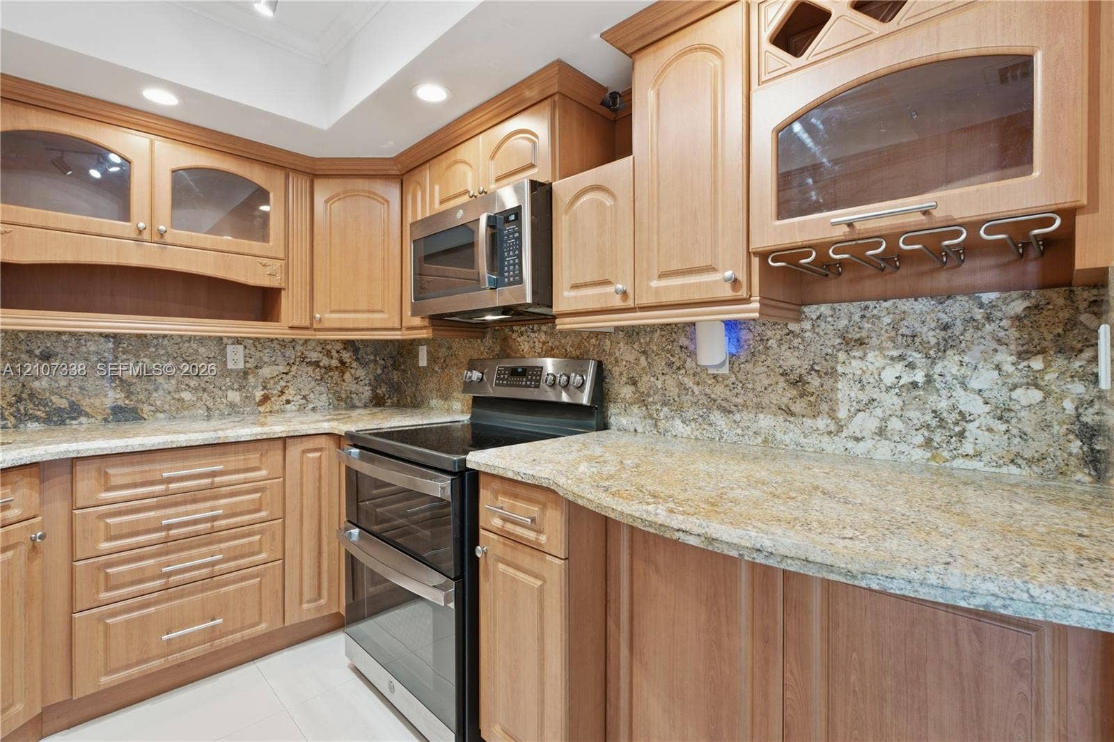 20355 NE 34th Court, #1824, Aventura, FL 33180 Kitchen featuring wood cabinetry, stone countertops, integrated wine glass rack, stainless steel double oven, and built-in microwave