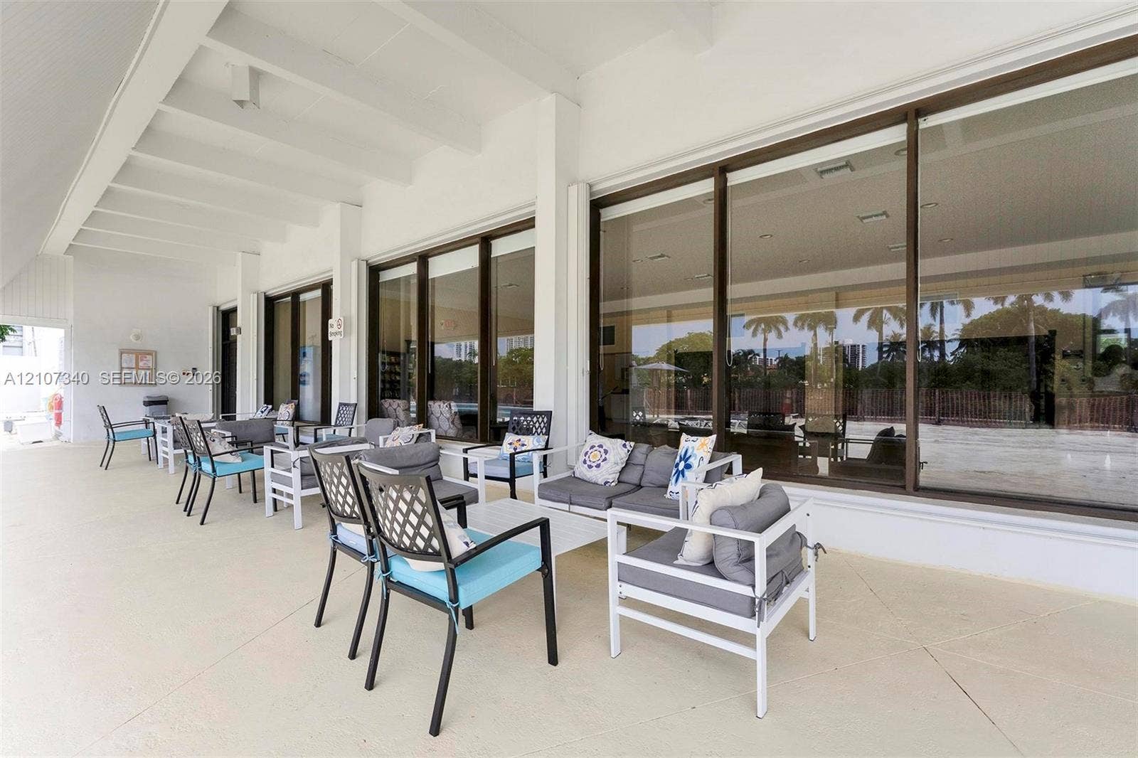 3401 N Country Club Drive, #406, Aventura, Aventura, FL 33180 Covered patio featuring a smooth concrete finish, white exposed beam ceiling, and extensive sliding glass wall panels