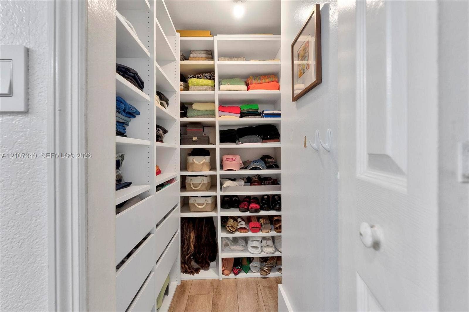 3401 N Country Club Drive, #406, Aventura, Aventura, FL 33180 Walk-in closet featuring white built-in shelving, integrated storage drawers, and wood-finish flooring