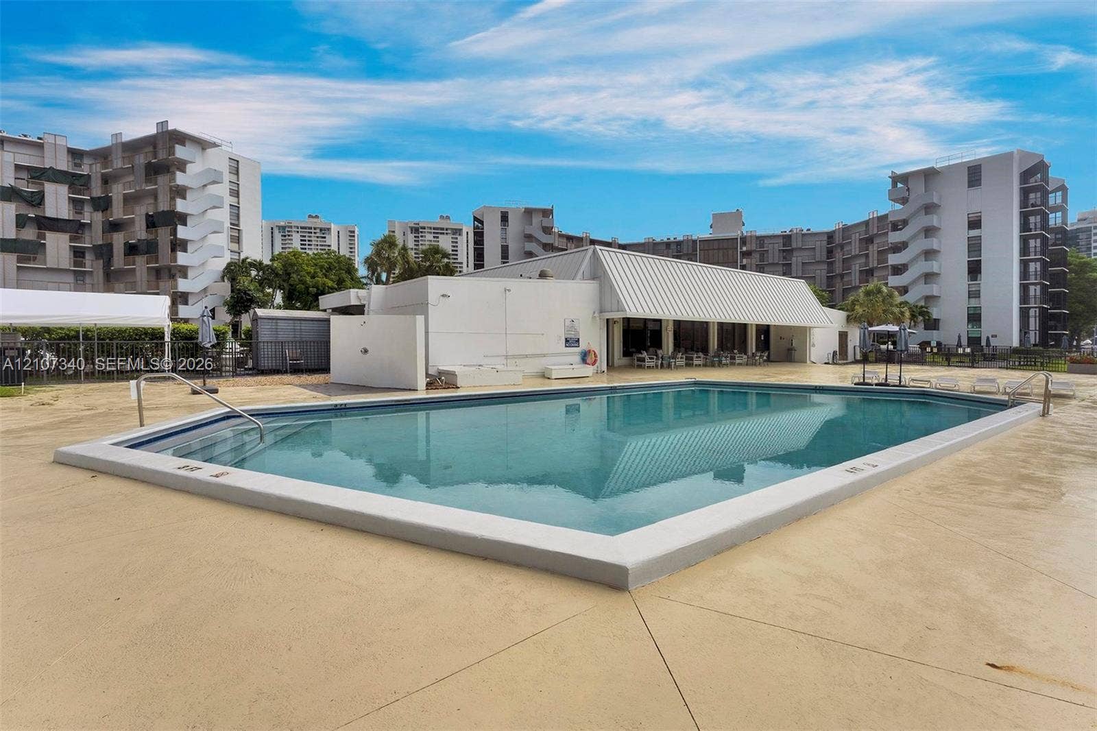 3401 N Country Club Drive, #406, Aventura, Aventura, FL 33180 Multi-story residential building exterior featuring a covered entryway, paved surface parking, and curated landscaping