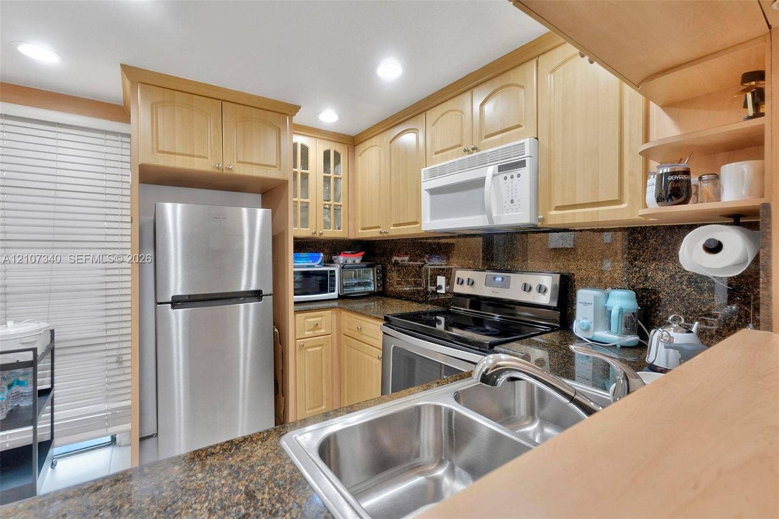 3401 N Country Club Drive, #406, Aventura, Aventura, FL 33180 Kitchen featuring light-finish cabinetry, stone-surface countertops, stainless steel appliances, a double-basin sink, and glass-paneled upper cabinets