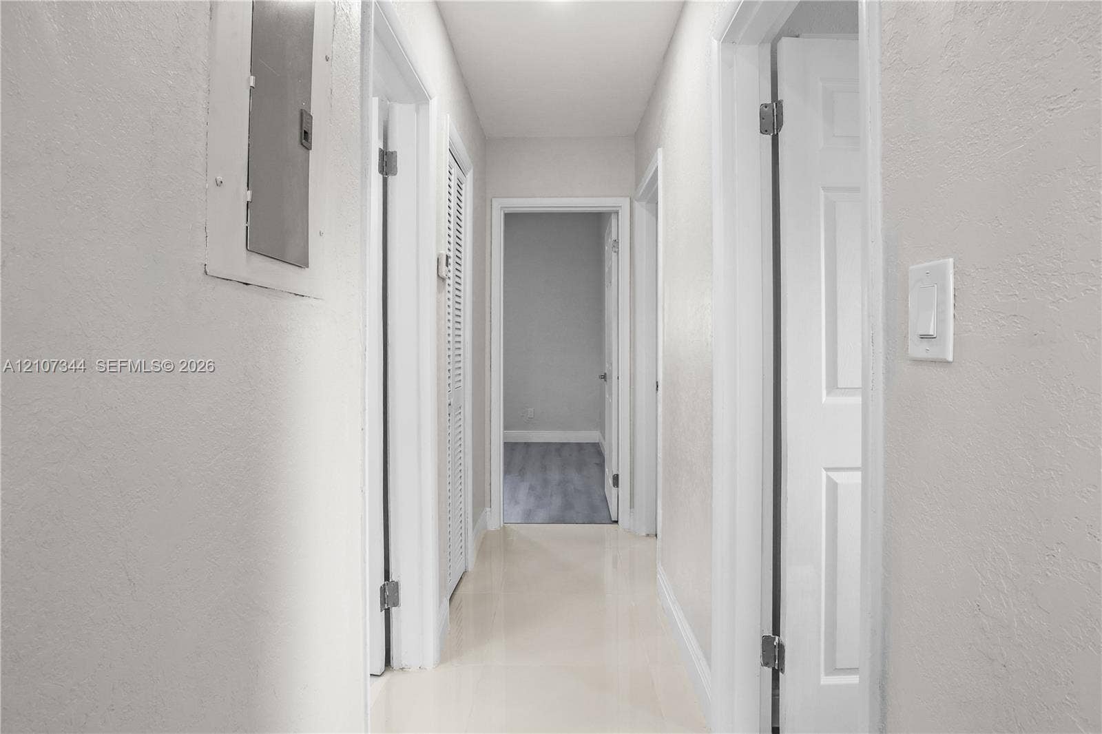 Hallway featuring neutral wall paint, multi-panel interior doors, louvered closet doors, and smooth-surface flooring