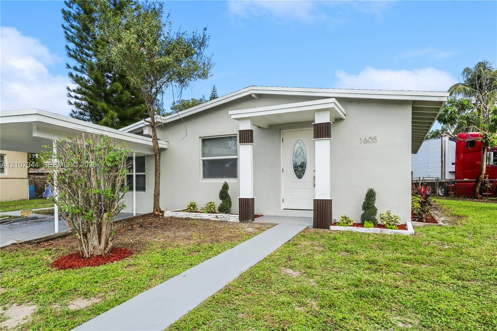 Single-story exterior featuring a covered carport, recessed entryway with architectural columns, and a concrete walkway
