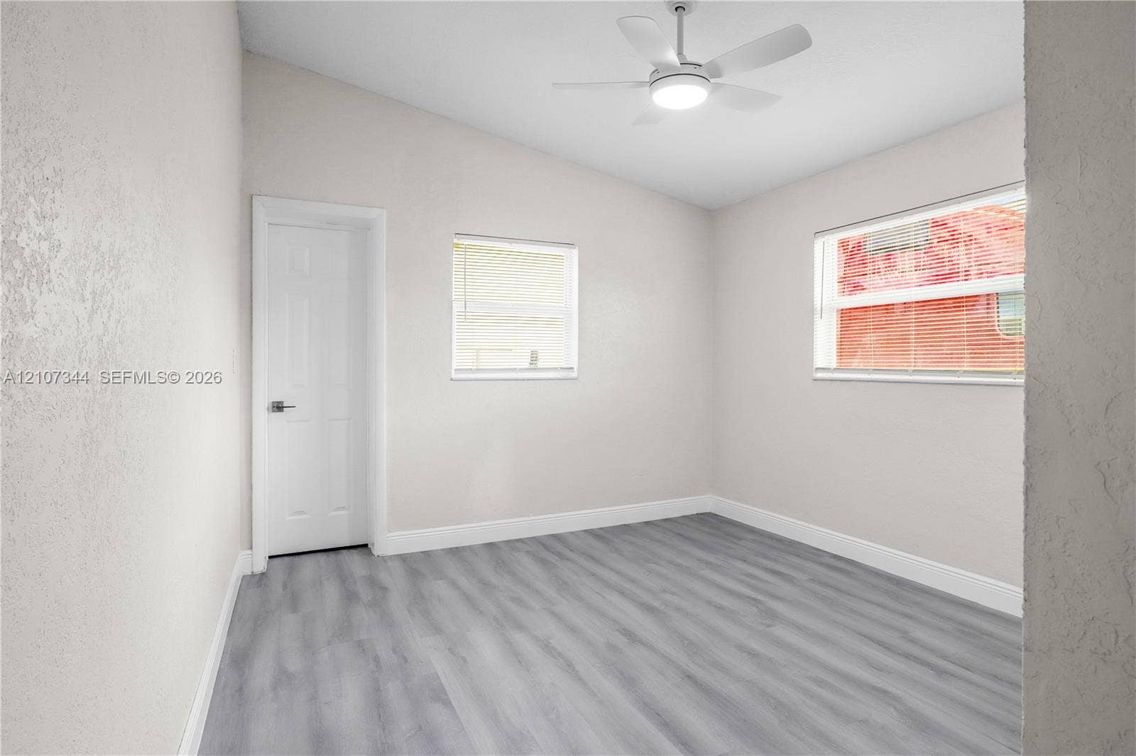 Interior space featuring vaulted ceilings, wood-finish flooring, two windows, and an integrated ceiling fan with light fixture