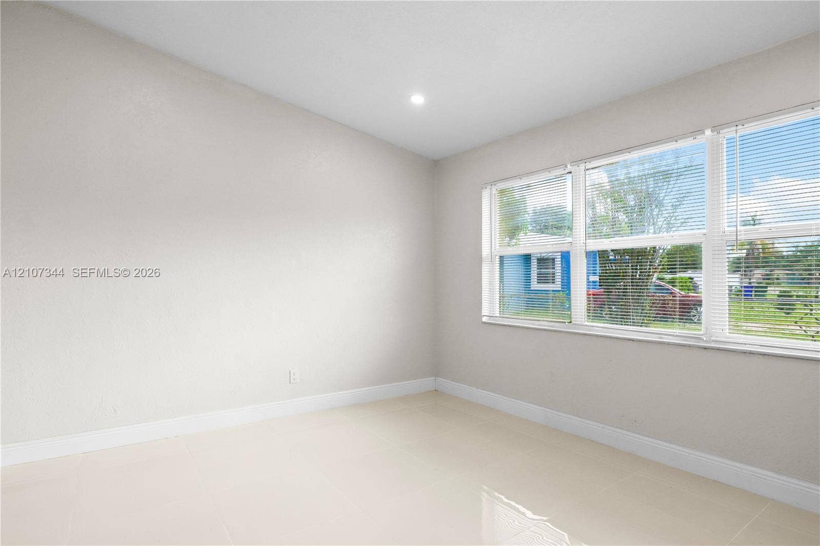 Interior space featuring neutral wall paint, polished tile flooring, and multiple windows with installed blinds