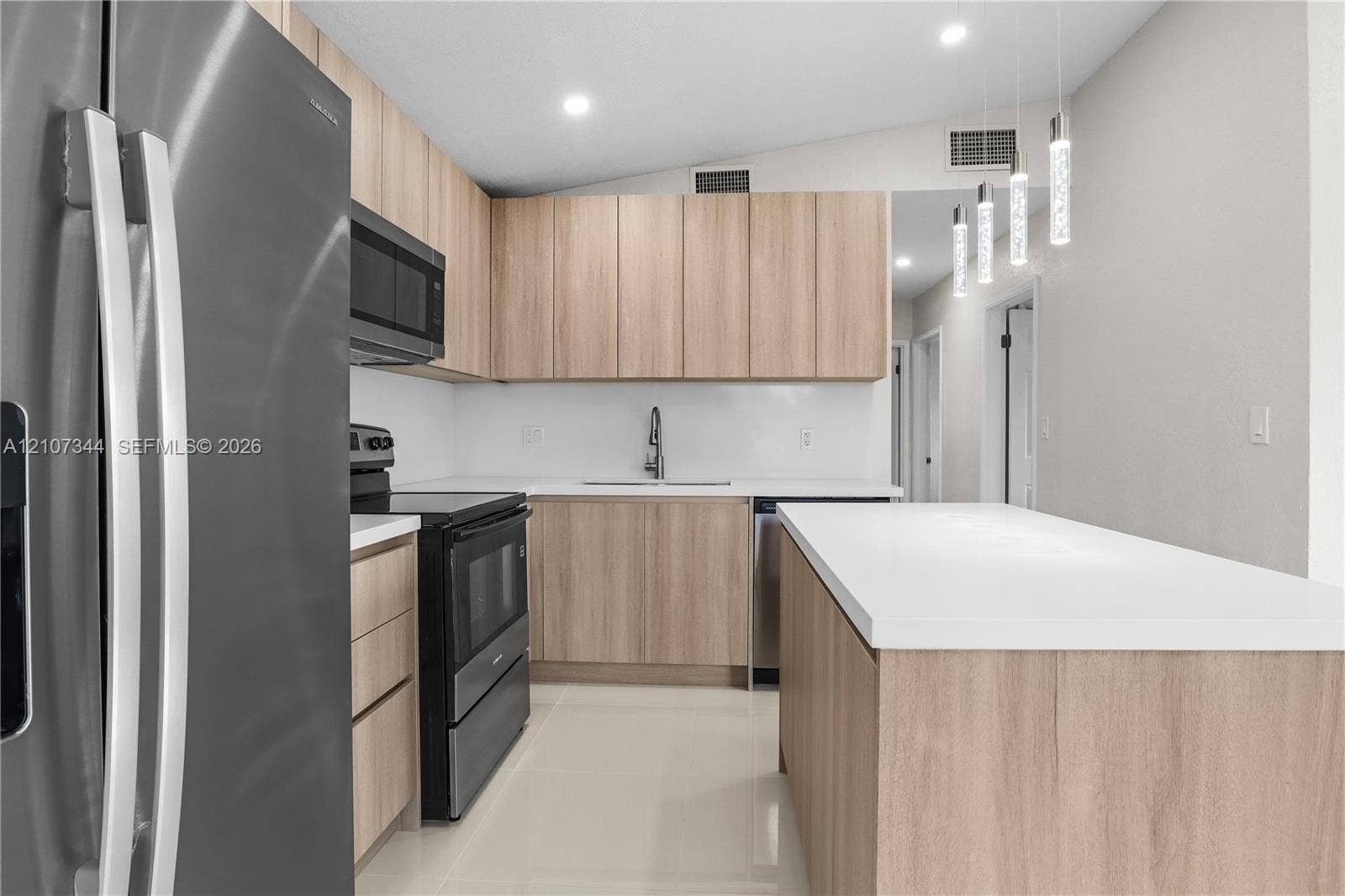 Kitchen featuring flat-panel wood-finish cabinetry, white countertops, stainless steel appliances, tile flooring, and multi-pendant lighting