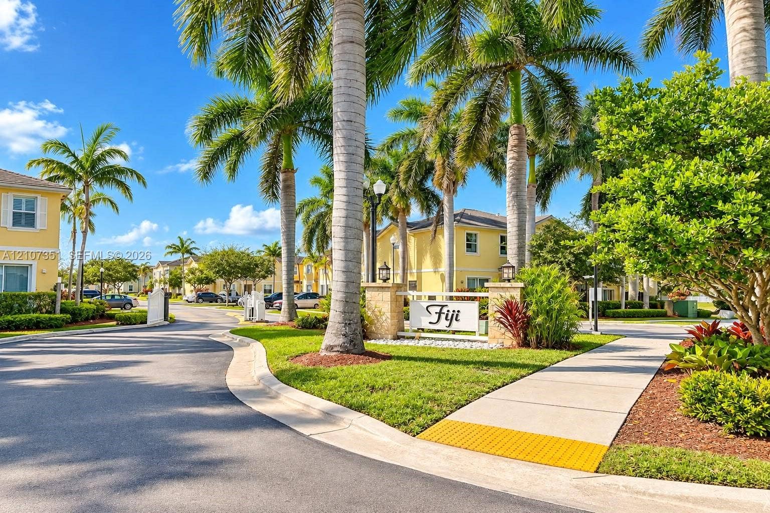 230 SE 29th Avenue, #1, Homestead, Homestead, FL 33033 Community entrance featuring stone pillars, mature palm trees, paved thoroughfare, and landscaped grounds