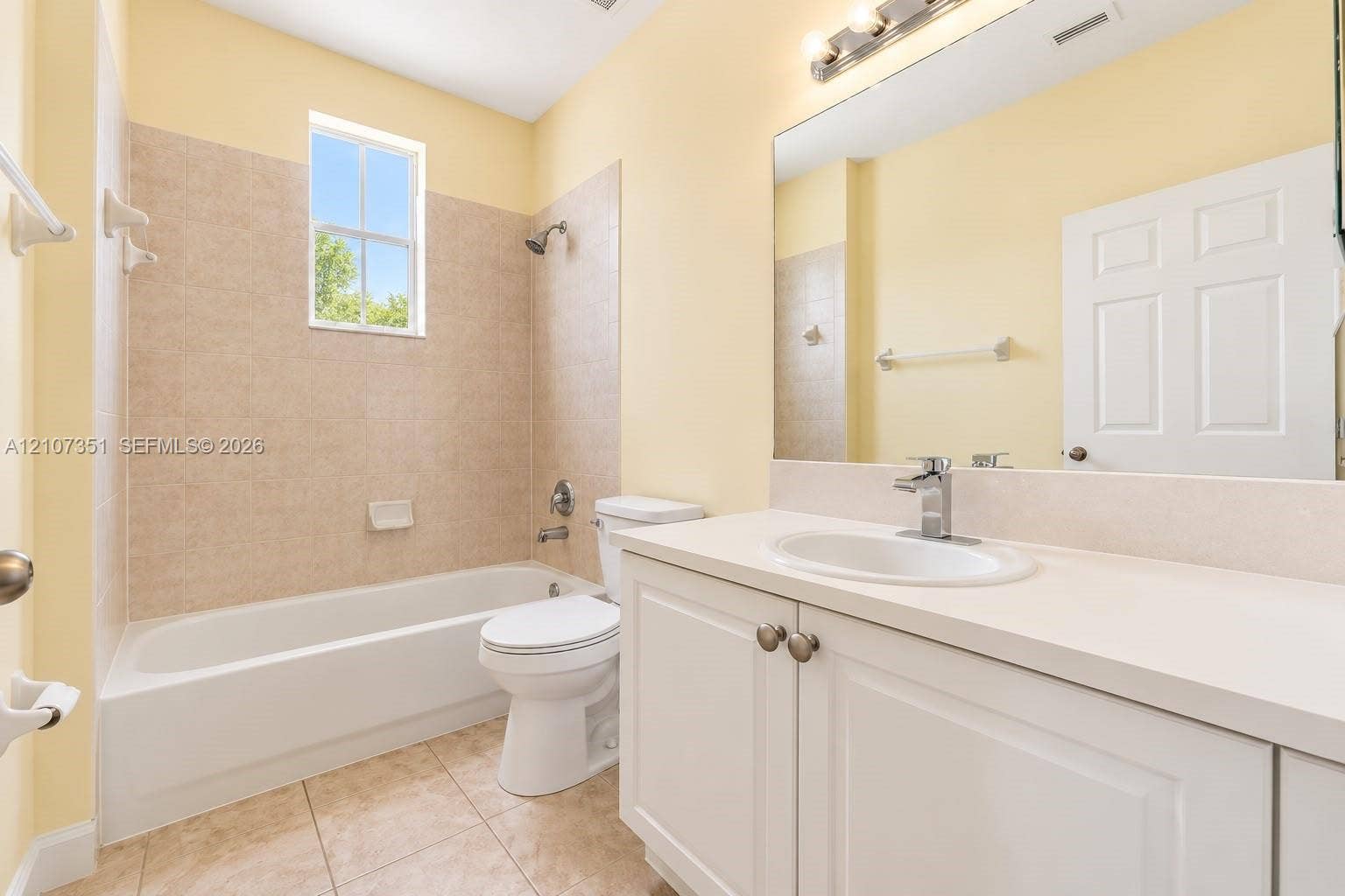 230 SE 29th Avenue, #1, Homestead, Homestead, FL 33033 Bathroom featuring a white vanity cabinet with an integrated sink and chrome faucet, a large wall-mounted mirror, a tiled shower-tub combination, and ceramic tile flooring