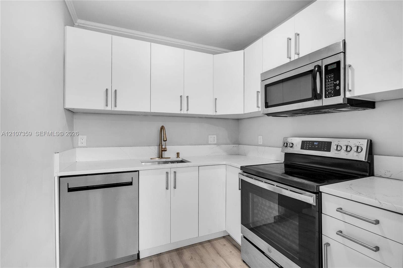 4500 NE 18th Avenue, Pompano Beach, Pompano Beach, FL 33064 Kitchen featuring white shaker-style cabinetry, solid-surface countertops, and stainless steel appliances including an over-the-range microwave
