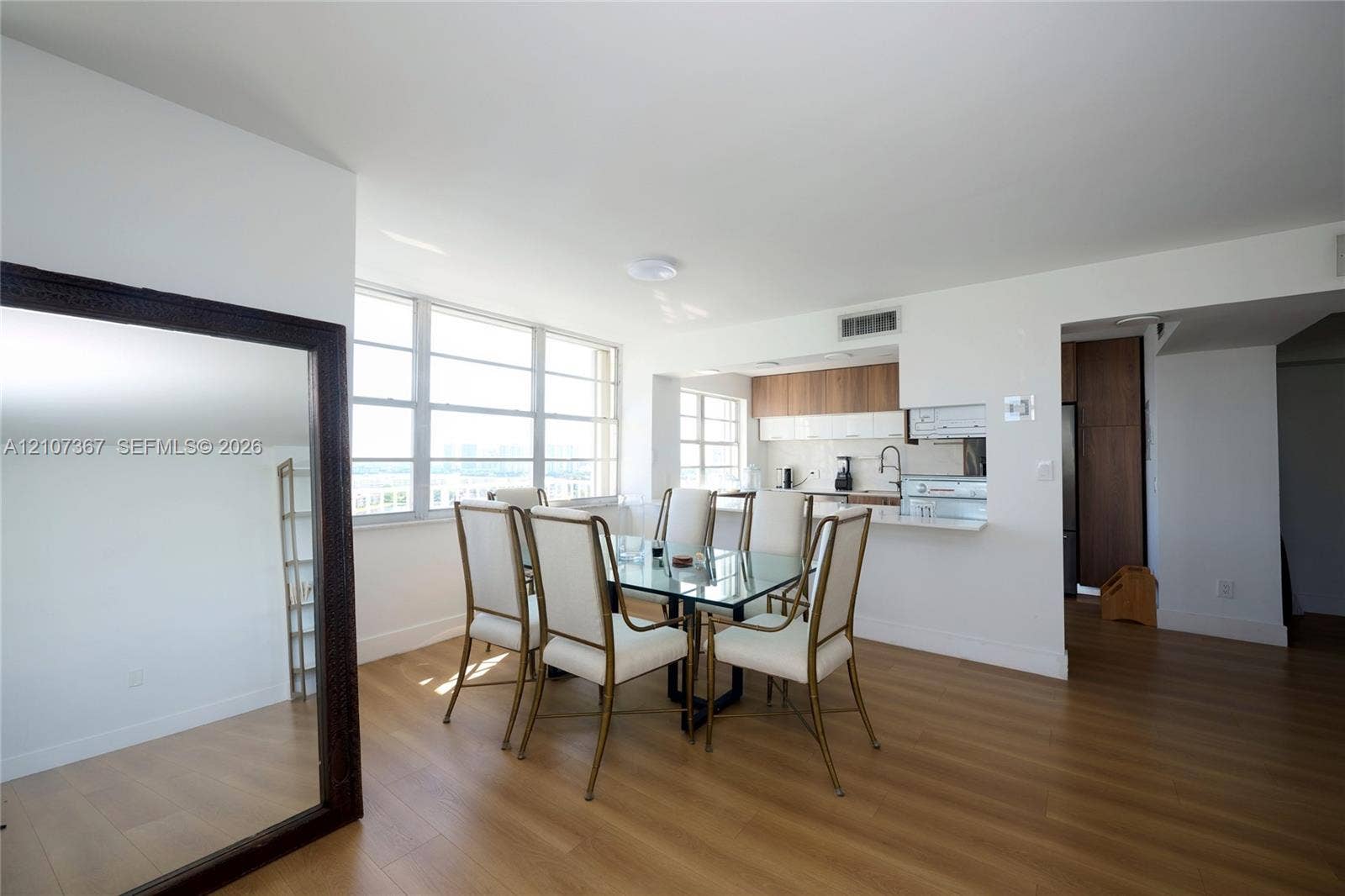 2851 NE 183rd Street, #1617E, Aventura, FL 33160 Open-concept area featuring wood-finish flooring, floor-to-ceiling windows, and a pass-through kitchen with flat-panel cabinetry