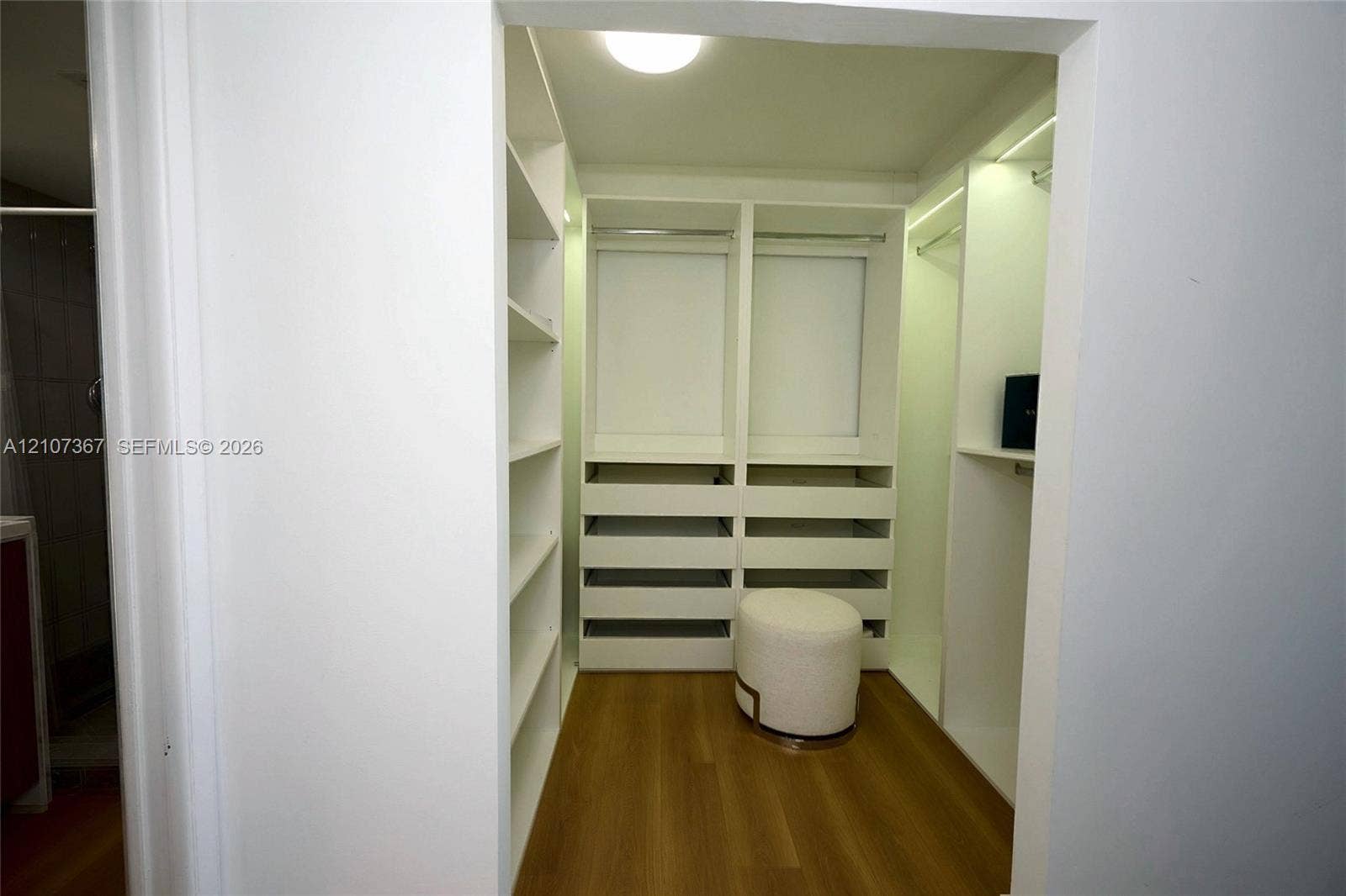 2851 NE 183rd Street, #1617E, Aventura, FL 33160 Walk-in closet featuring white built-in shelving, integrated dresser drawers, hanging rods, recessed ceiling lighting, and wood-finish flooring