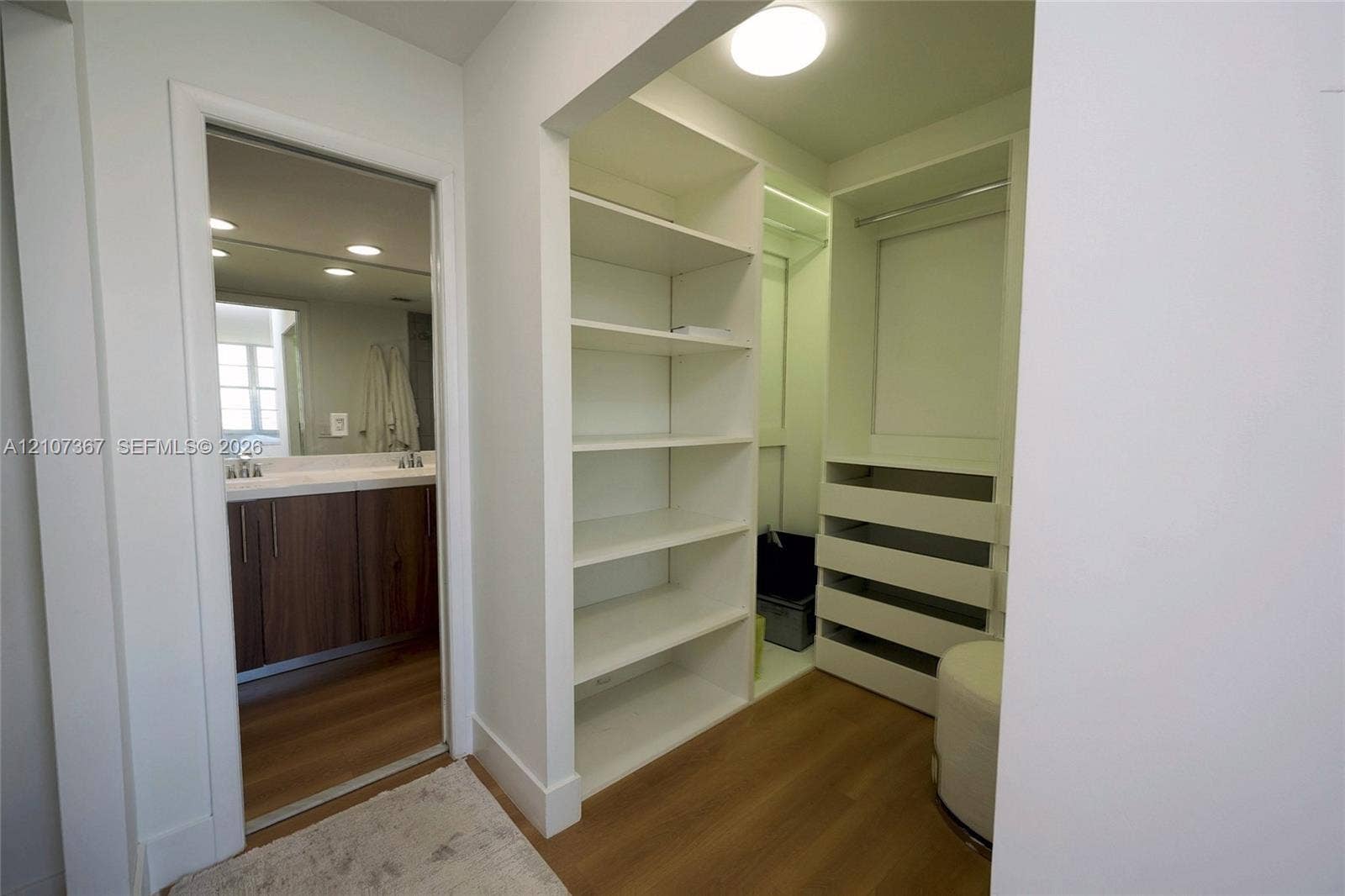 2851 NE 183rd Street, #1617E, Aventura, FL 33160 Walk-in closet featuring white built-in shelving and tiered storage drawers, wood-finish flooring, and flush-mount ceiling lighting