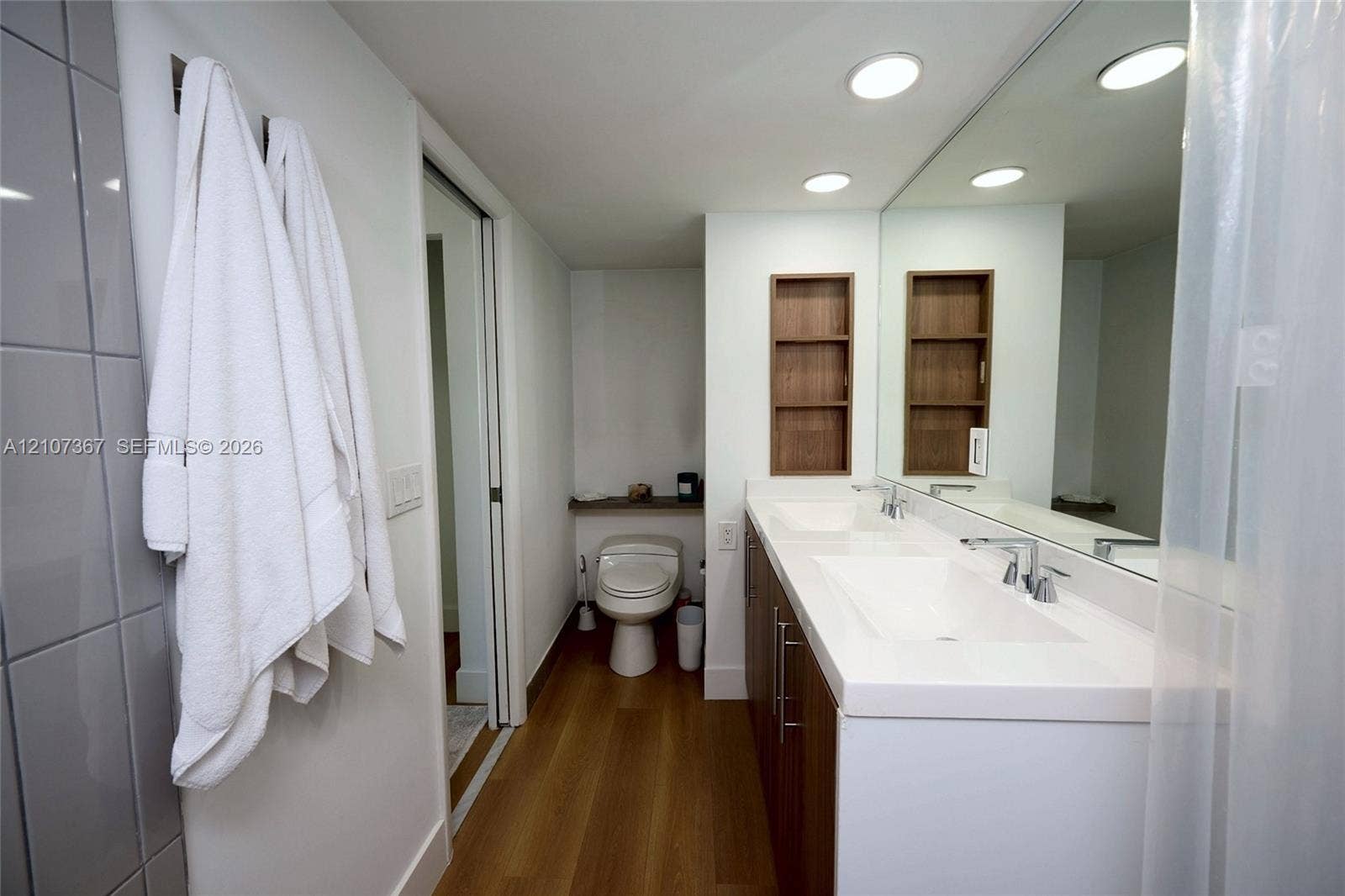 2851 NE 183rd Street, #1617E, Aventura, FL 33160 Double vanity featuring white integrated sinks, wood-finish cabinetry, recessed lighting, and wall-recessed shelving