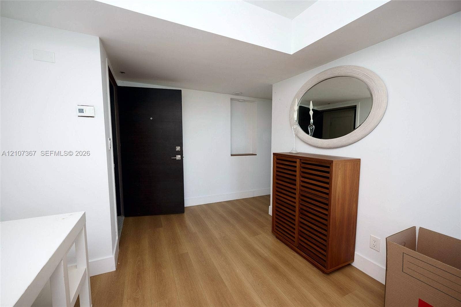 2851 NE 183rd Street, #1617E, Aventura, FL 33160 Entryway featuring wood-finish flooring, a dark-finish solid core door with a matte metallic handle, and a built-in recessed niche