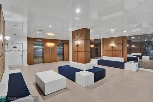 1800 N Andrews Avenue, #9K, Fort Lauderdale, Fort Lauderdale, FL 33311 Lobby area featuring high-gloss reflective ceilings, wood-panel wall accents, recessed lighting, dual elevator access, and floor-to-ceiling mirror panels