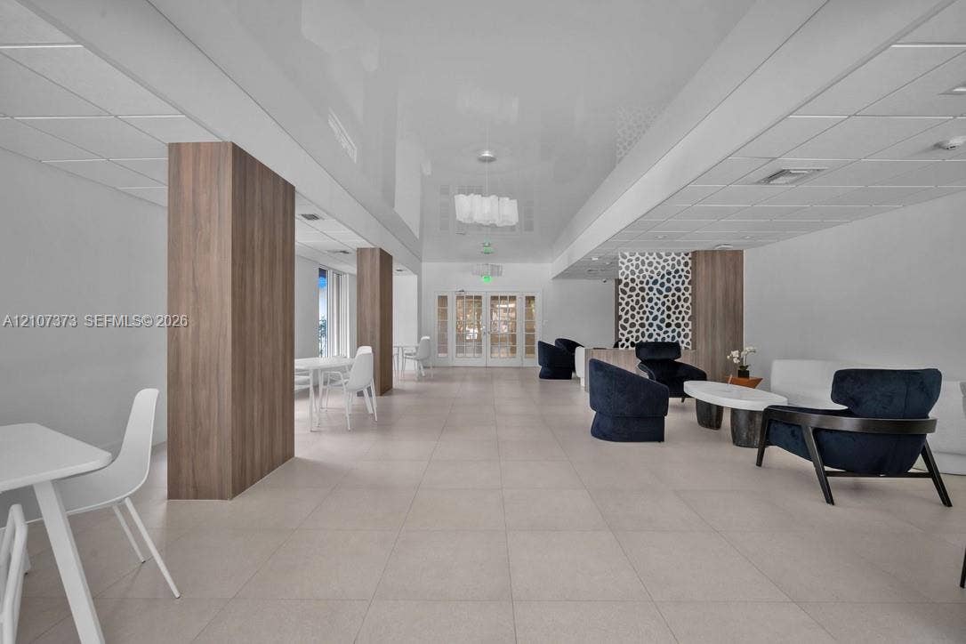 1800 N Andrews Avenue, #9K, Fort Lauderdale, Fort Lauderdale, FL 33311 Open-concept floor plan featuring large-format ceramic tile flooring, wood-finish structural columns, recessed ceiling lighting, and a decorative patterned accent wall