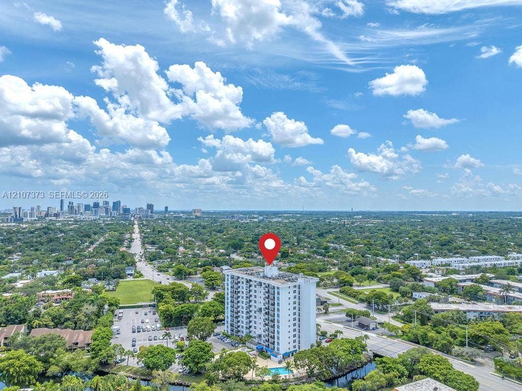 1800 N Andrews Avenue, #9K, Fort Lauderdale, Fort Lauderdale, FL 33311 High-rise building featuring a white facade, a dedicated surface parking lot, an on-site swimming pool, and mature tree-lined surroundings