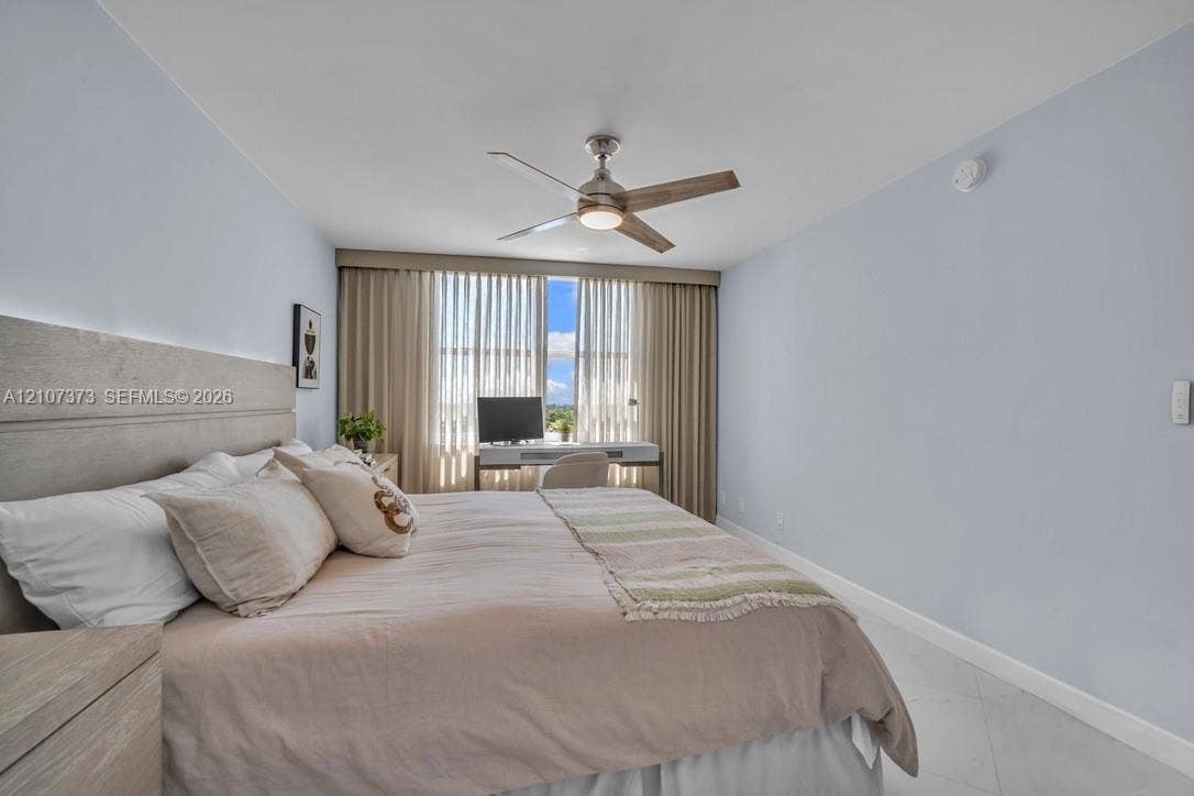 1800 N Andrews Avenue, #9K, Fort Lauderdale, Fort Lauderdale, FL 33311 Light-filled room featuring large window panels with floor-to-ceiling drapery, neutral wall finishes, tile flooring, and a modern brushed-metal ceiling fan with integrated lighting