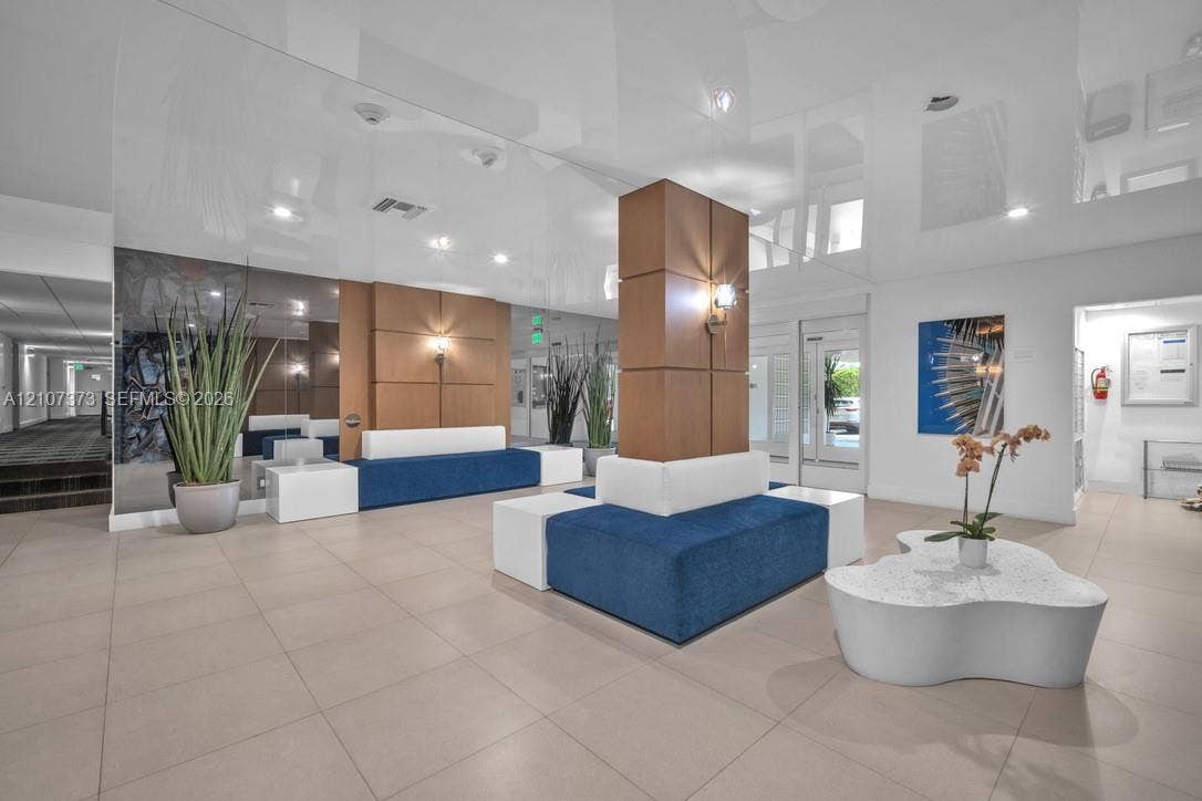 1800 N Andrews Avenue, #9K, Fort Lauderdale, Fort Lauderdale, FL 33311 Lobby featuring high-gloss ceilings, large-format tile flooring, mirrored wall accents, and wood-paneled structural columns with integrated sconce lighting