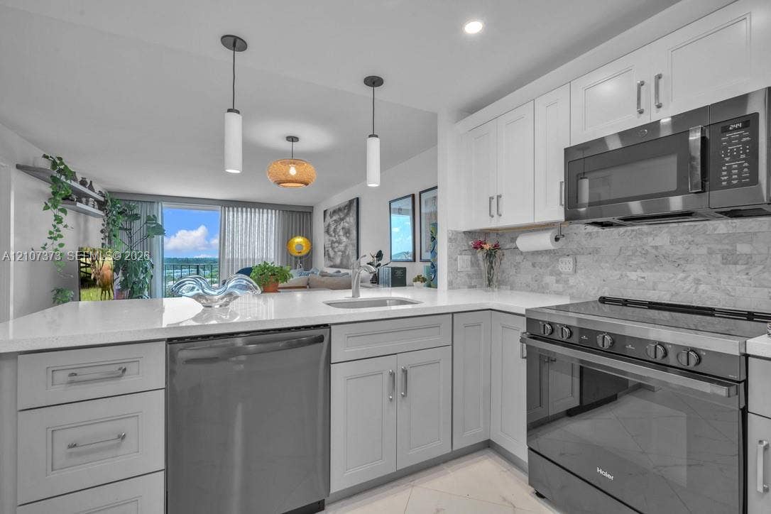 1800 N Andrews Avenue, #9K, Fort Lauderdale, Fort Lauderdale, FL 33311 Kitchen featuring white shaker-style cabinetry, quartz countertops, stone tile backsplash, stainless steel appliances, and dual pendant lighting