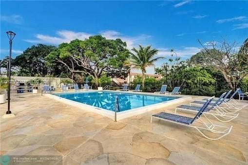 1800 N Andrews Avenue, #9K, Fort Lauderdale, Fort Lauderdale, FL 33311 Rectangular swimming pool featuring a flagstone patio, perimeter metal fencing, and mature trees