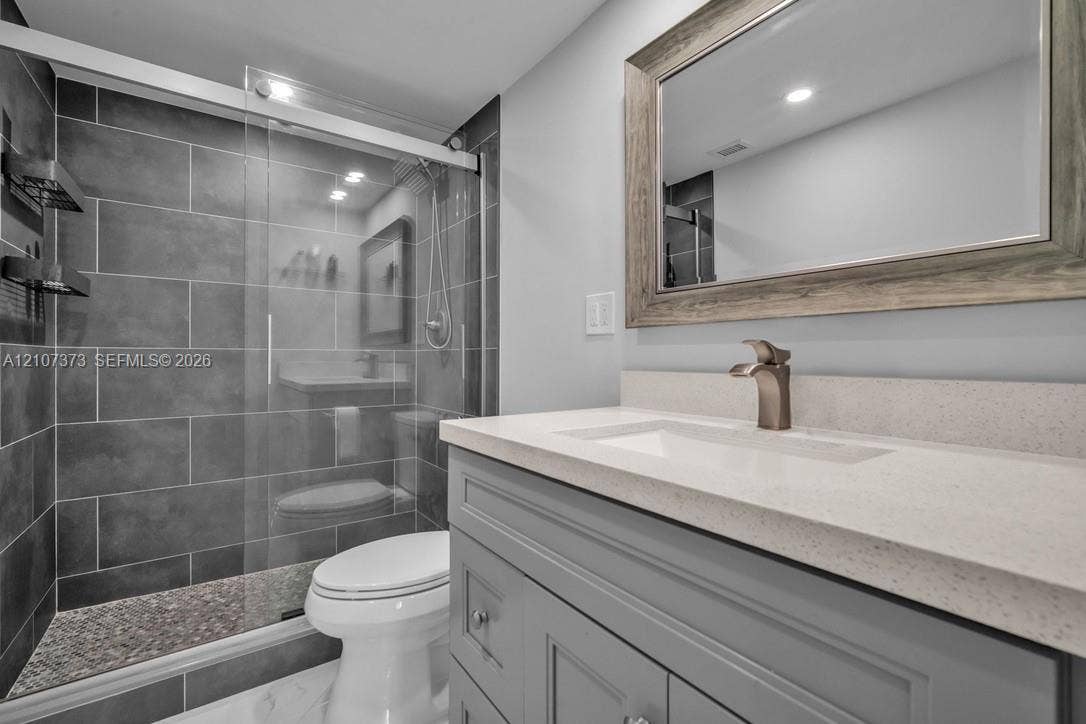 1800 N Andrews Avenue, #9K, Fort Lauderdale, Fort Lauderdale, FL 33311 Bathroom featuring a vanity with a light-toned countertop, rectangular undermount sink, and brushed metal faucet, complemented by a walk-in shower with large-format grey tile surround and a glass sliding door