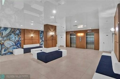 1800 N Andrews Avenue, #9K, Fort Lauderdale, Fort Lauderdale, FL 33311 Lobby featuring high-gloss ceiling, stone-accented walls, wood-paneled columns, built-in seating, and metallic elevator doors