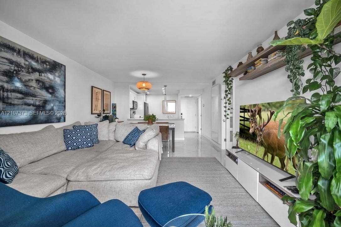 1800 N Andrews Avenue, #9K, Fort Lauderdale, Fort Lauderdale, FL 33311 Open-concept living space featuring high-gloss tile flooring, white built-in media cabinetry, and an integrated wall-mounted wood-finish floating shelf