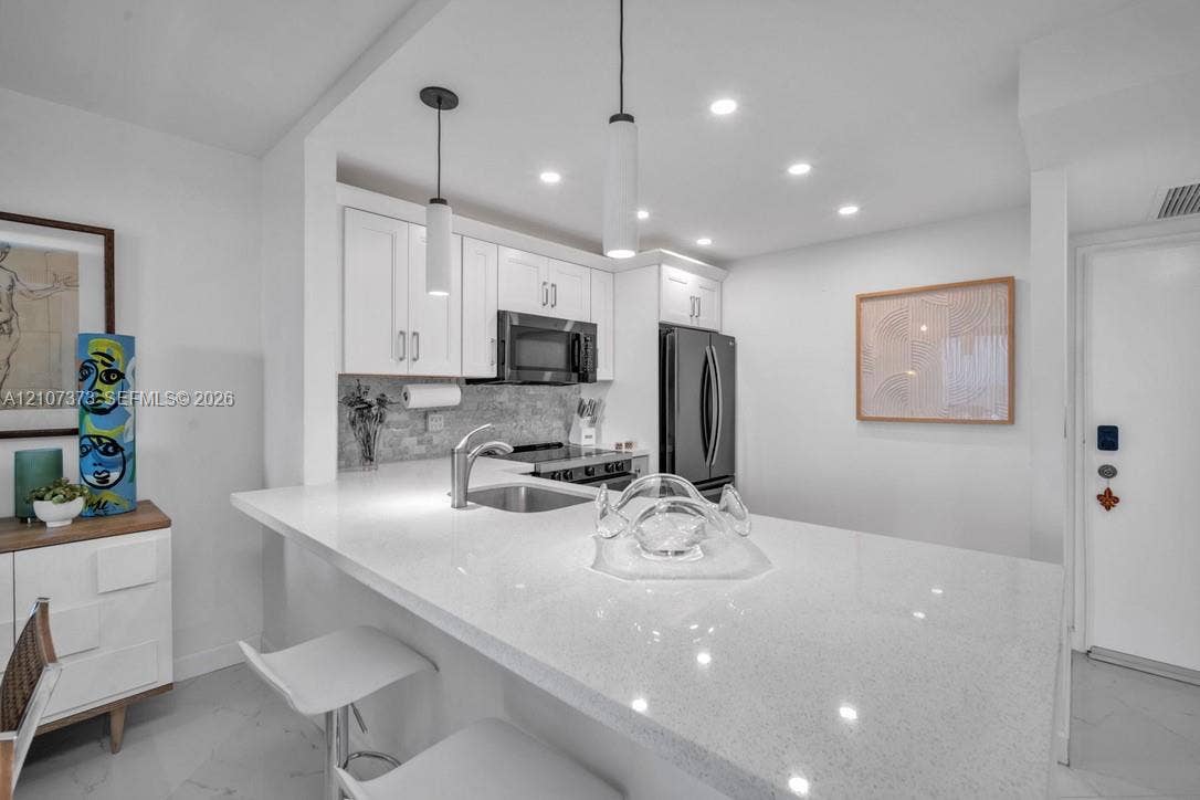 1800 N Andrews Avenue, #9K, Fort Lauderdale, Fort Lauderdale, FL 33311 Kitchen featuring white shaker cabinetry, stone-surface countertop with integrated sink, stainless steel appliances, and pendant lighting