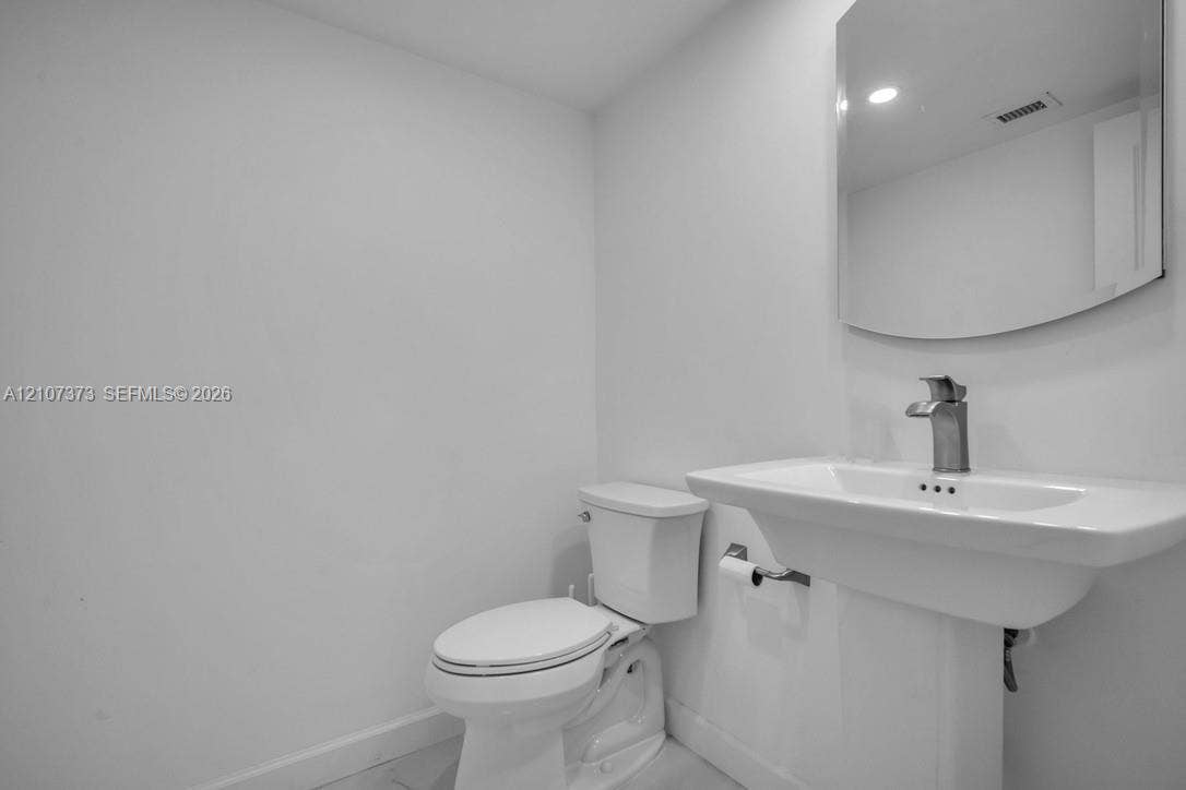 1800 N Andrews Avenue, #9K, Fort Lauderdale, Fort Lauderdale, FL 33311 Half Bathroom Pedestal sink featuring a polished chrome faucet, wall-mounted mirror, and white ceramic toilet
