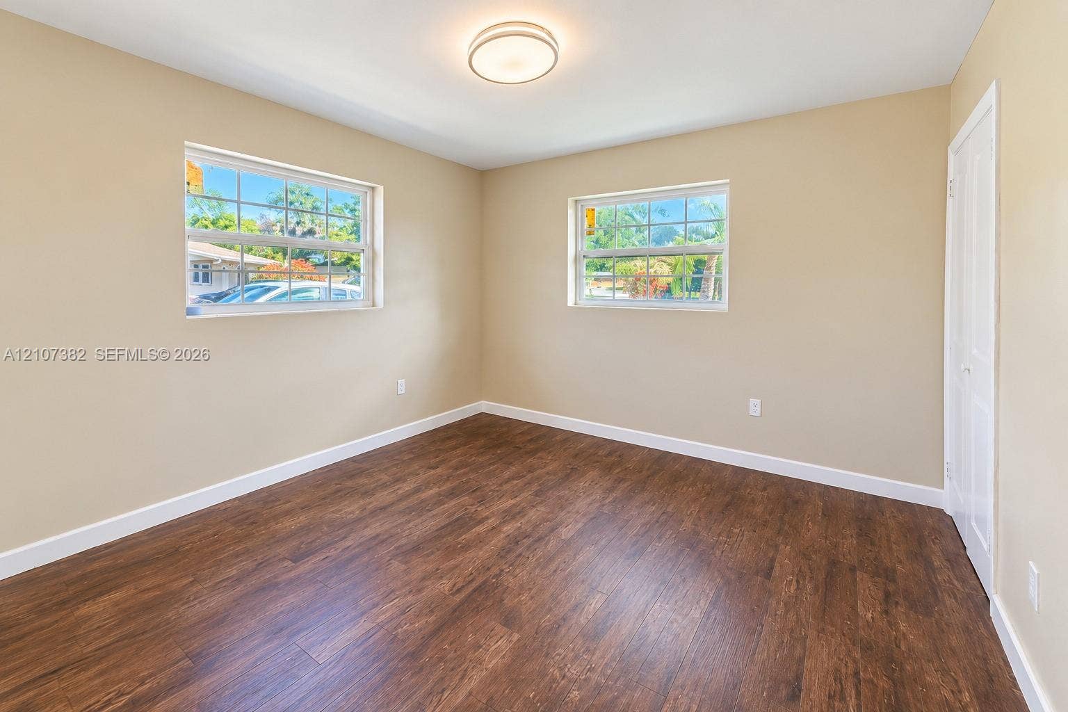 859 Caroline Circle, Palm Beach, FL 33413 Neutral-toned interior room featuring wood-finish flooring, two dual-pane windows with muntins, and a ceiling-mounted light fixture