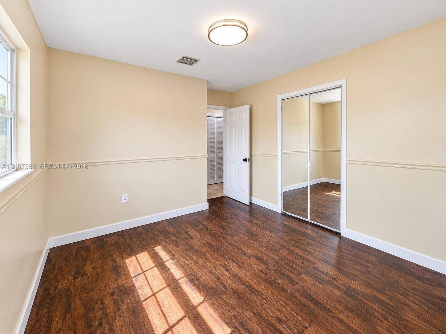 859 Caroline Circle, Palm Beach, FL 33413 Wood-finish flooring, dual-panel sliding mirror closet doors, chair rail molding, and a flush-mount ceiling light fixture