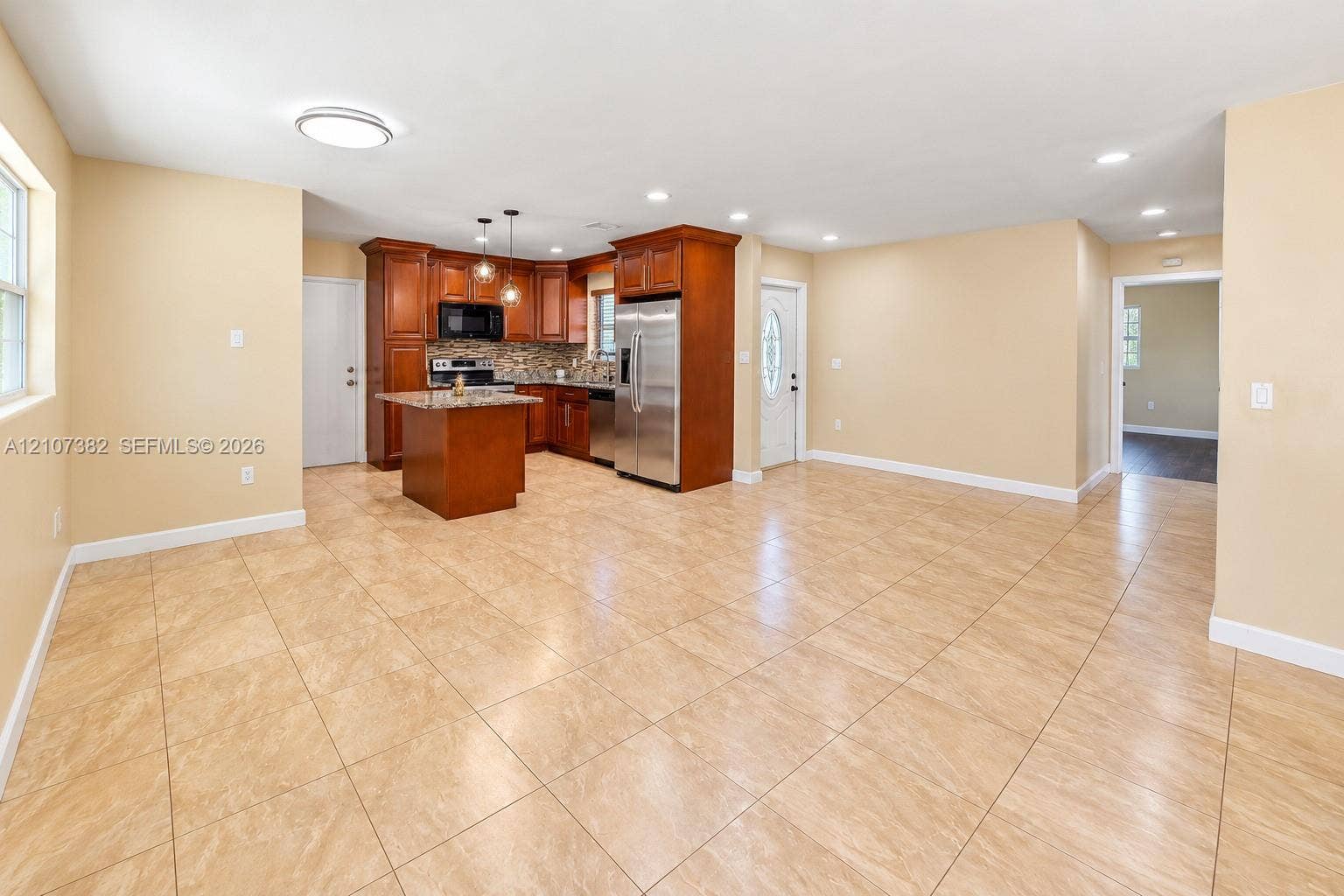 859 Caroline Circle, Palm Beach, FL 33413 Kitchen featuring wood cabinetry, stone-finish countertops, stainless steel appliances, a center island, and neutral tile flooring