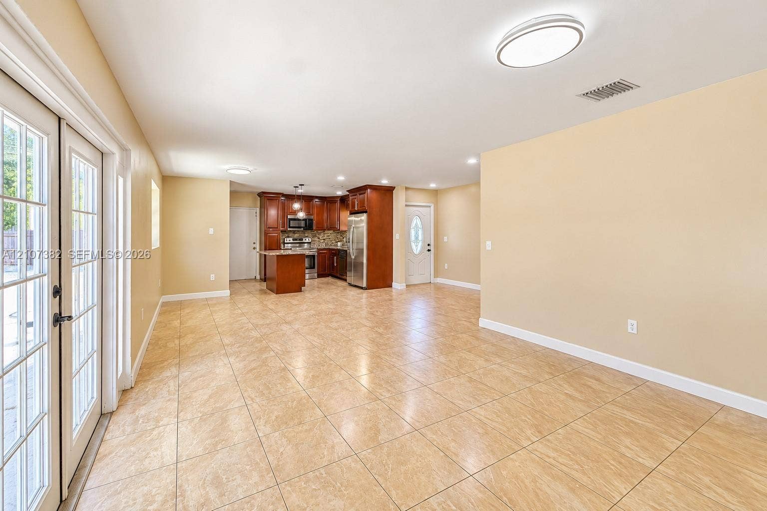 859 Caroline Circle, Palm Beach, FL 33413 Open-concept interior featuring large-format tile flooring, recessed lighting, wood-finish cabinetry, stainless steel appliances, and glass-paned double doors