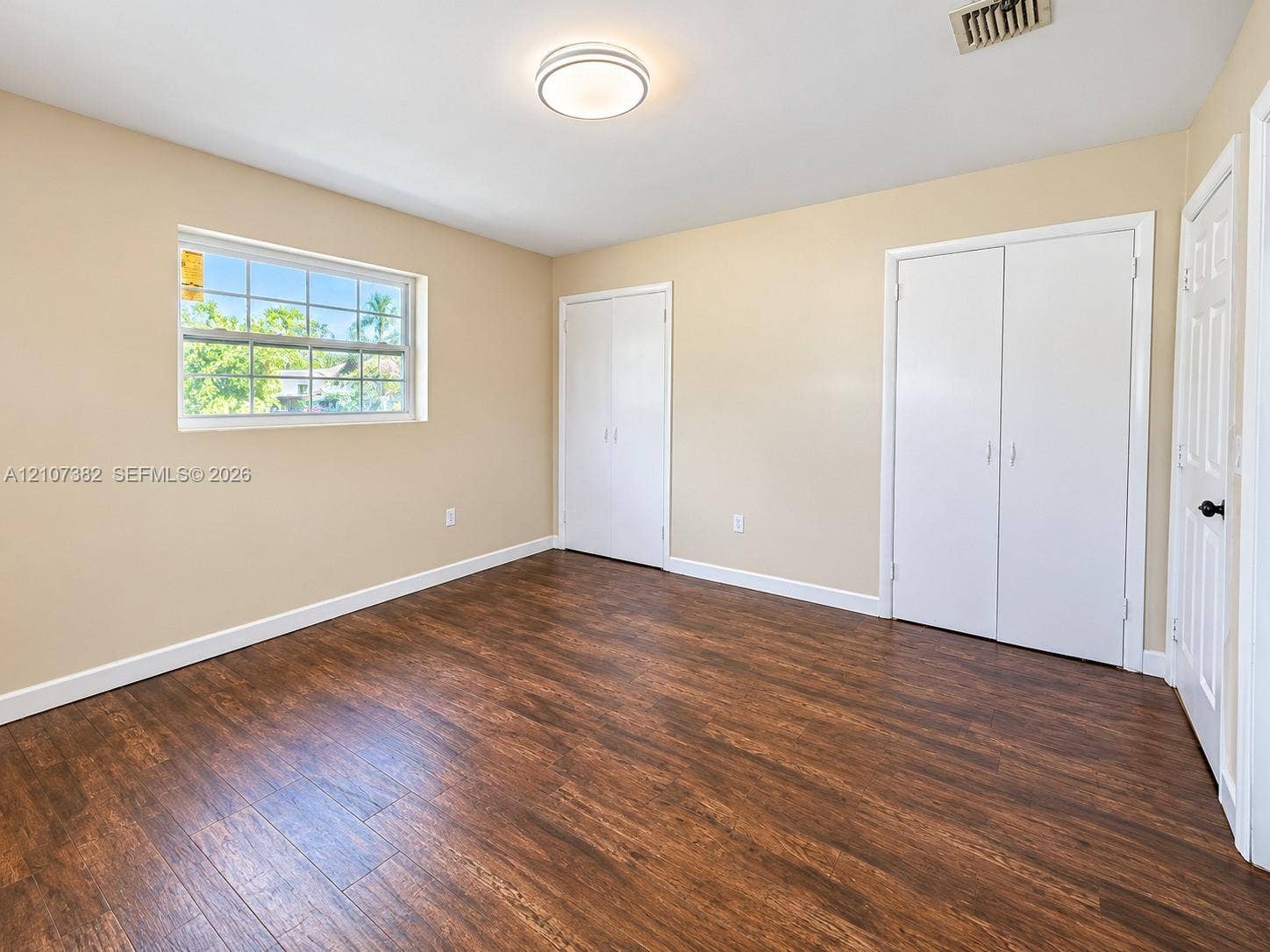859 Caroline Circle, Palm Beach, FL 33413 Interior room featuring wood-finish flooring, dual built-in closets with white paneled doors, and a multi-pane window
