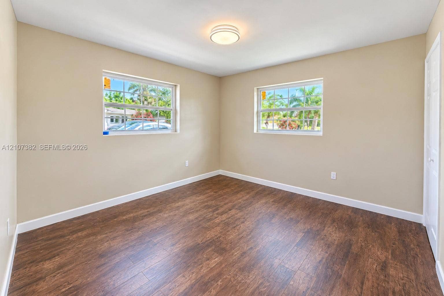 859 Caroline Circle, Palm Beach, FL 33413 Room featuring wood-finish flooring, dual windows with grid detailing, neutral wall tones, and a central flush-mount ceiling light fixture