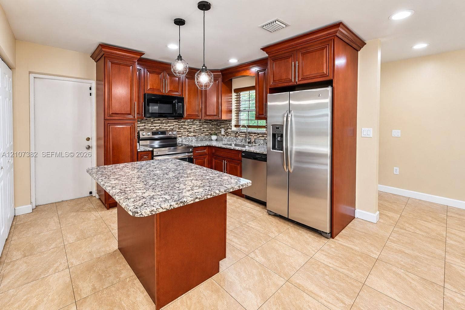 859 Caroline Circle, Palm Beach, FL 33413 Kitchen featuring rich wood cabinetry, stone-surface countertops, stainless steel appliances, a central island, and glass pendant lighting